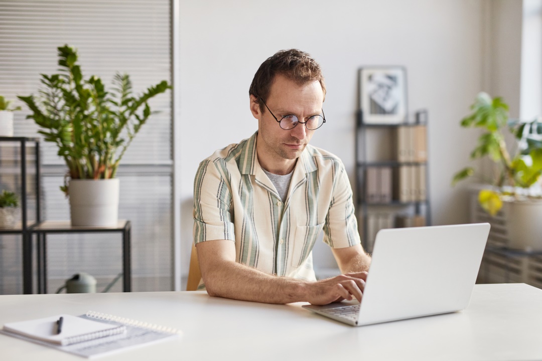 Hombre con lentes con una laptop eligiendo proveedor de correo electronico