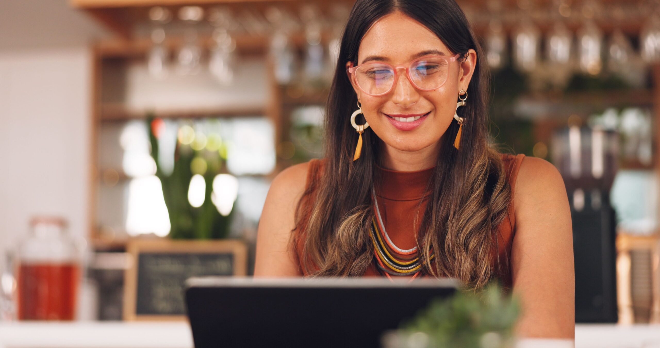 Mujer con lentes y laptop viendo tutoriales de hosting