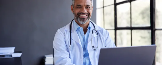 Doctor utilizando laptop para diseñar pagina web gratis, mostrando cómo profesionales de salud pueden crear su presencia digital fácilmente.